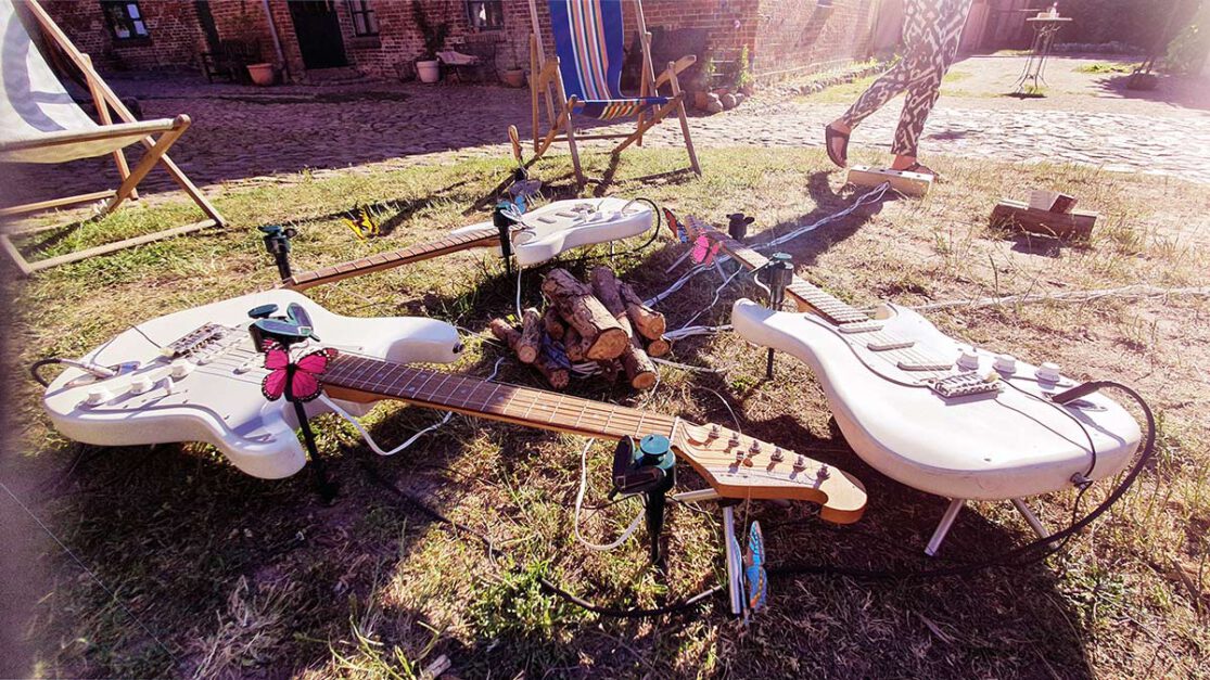 Three guitars are played by various small rotating butterflies